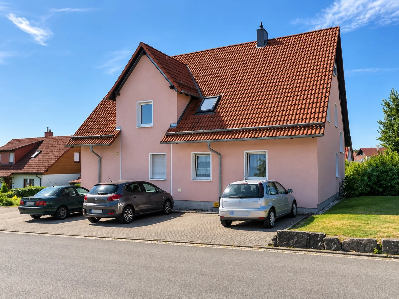 Straßenseite des Mehrfamilienhauses mit den Stellplätzen vor dem Gebäude