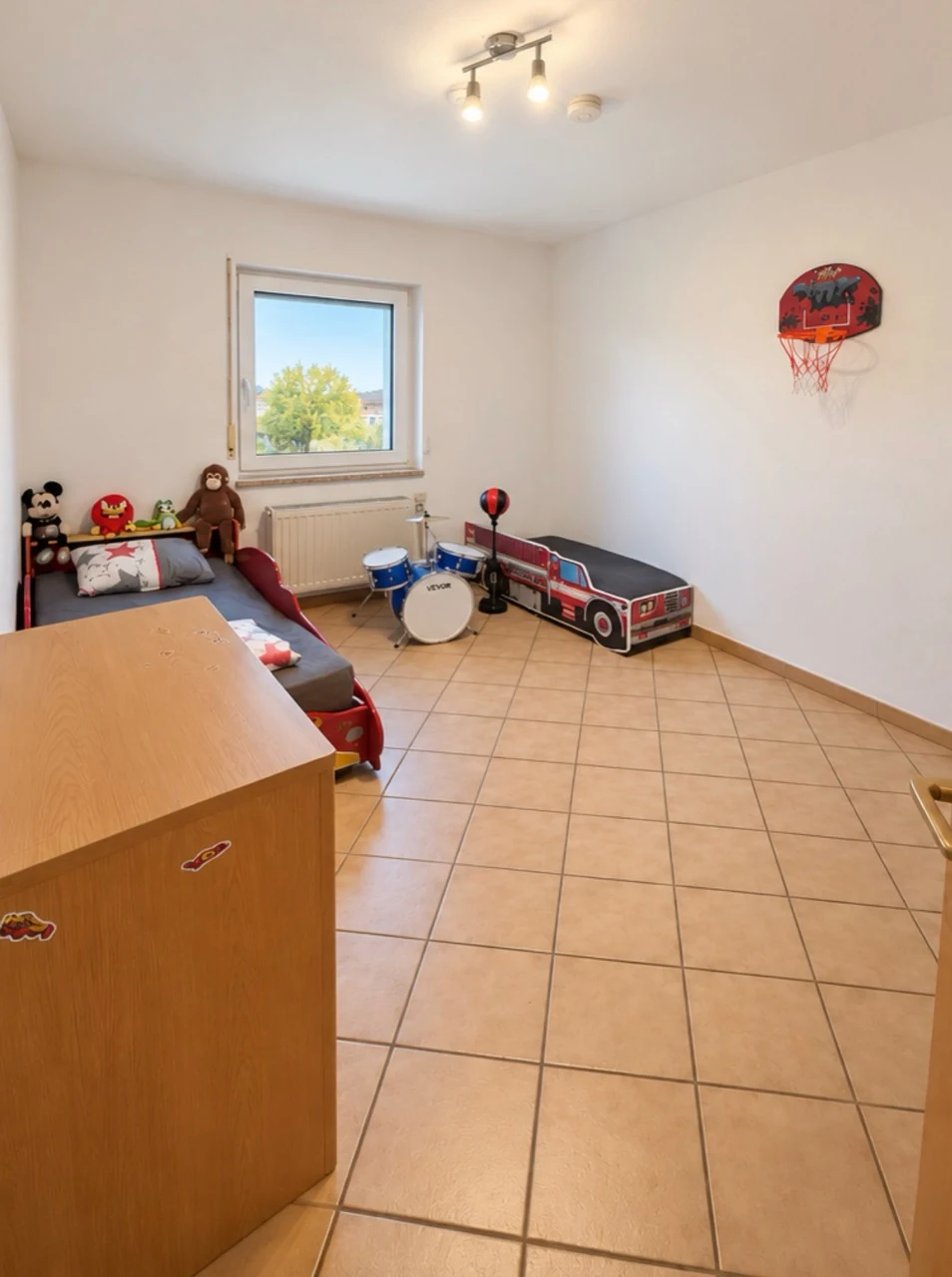 Als Kinderzimmer eingerichteter Raum mit Fenster und gefliestem Boden