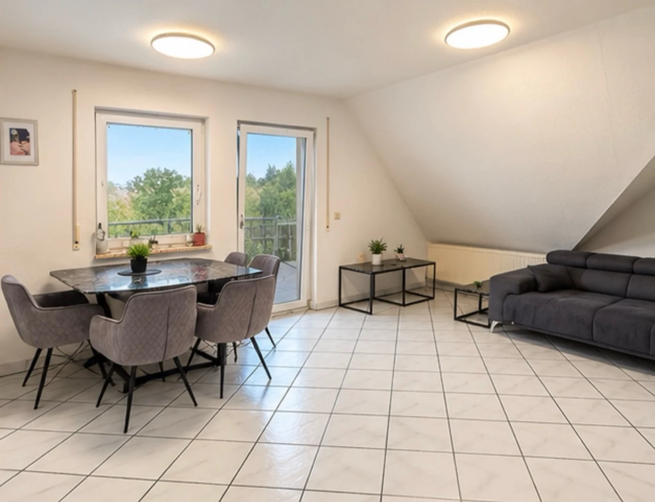 Helles gefliestes Wohnzimmer mit Esstisch, Sofa und Tür zum Balkon